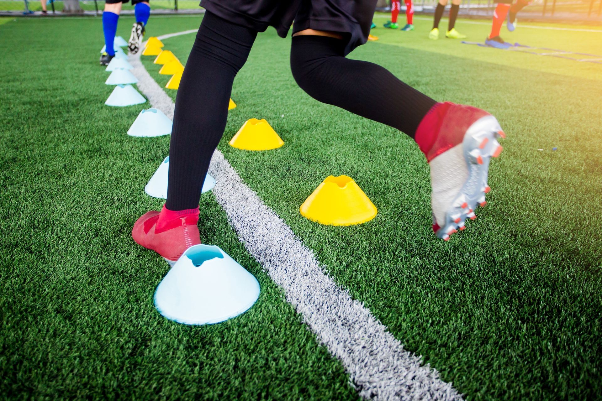 Young boy soccer players Jogging and jump between many marker cones. Soccer player training.